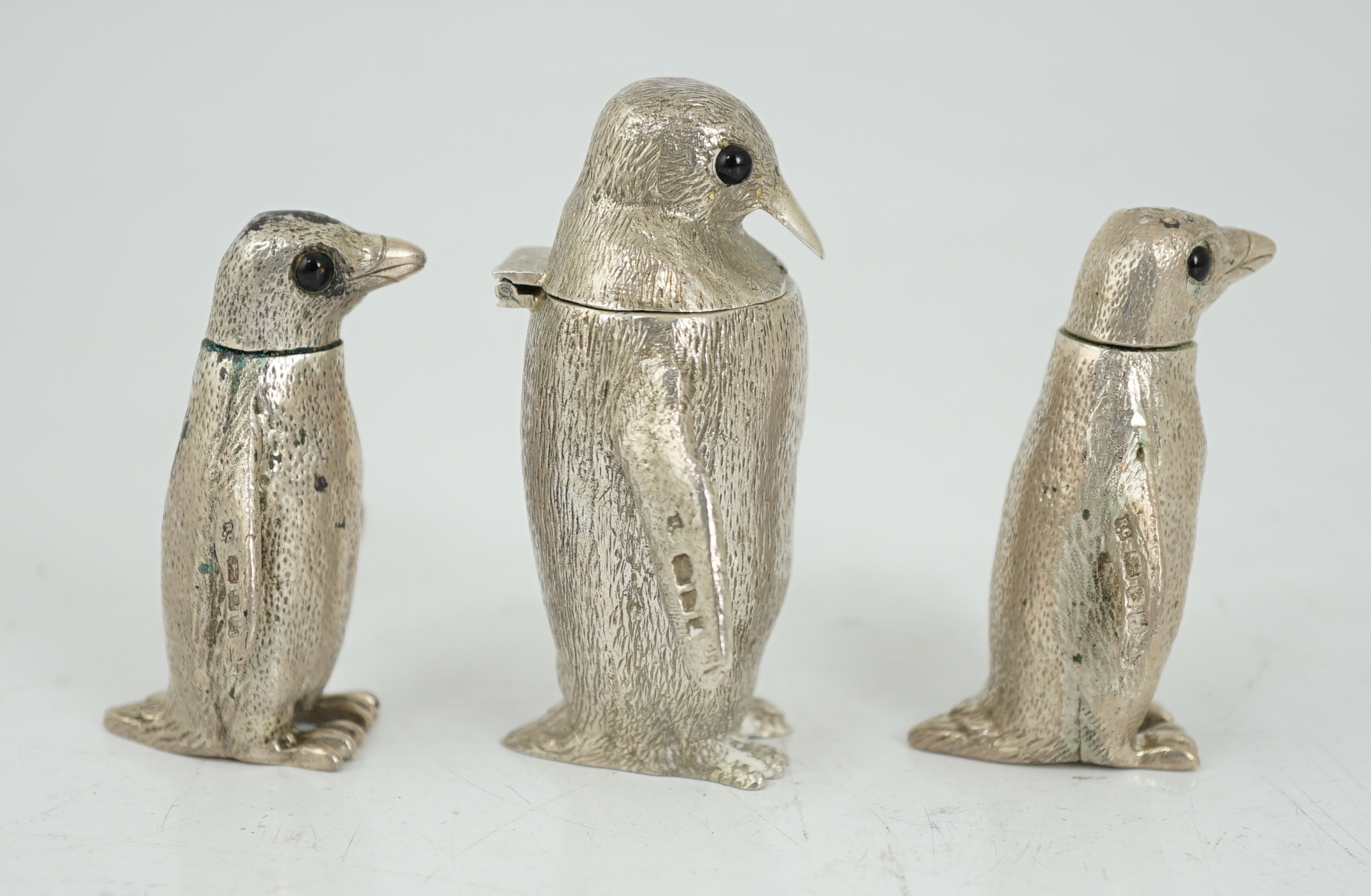 An Elizabeth II graduated suite of three novelty silver condiments, modelled as penguins, by William Comyns & Sons Ltd
